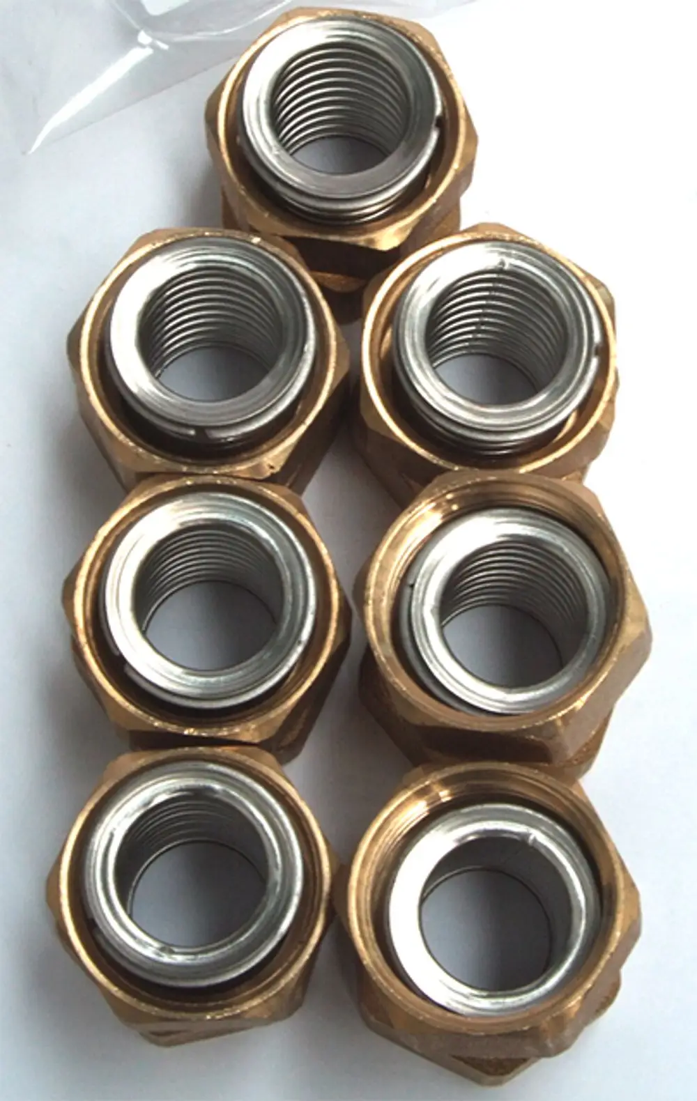Sechs metallene Rohrmuttern mit Innengewinde in einer Anordnung. Die Muttern bestehen aus Messing und sind für Rohrverbindungen geeignet, möglicherweise für Daikin Produkte.